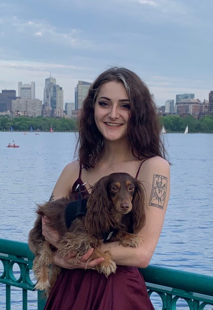 nina smiles fr the camera in front of boston with moose the voxel dog